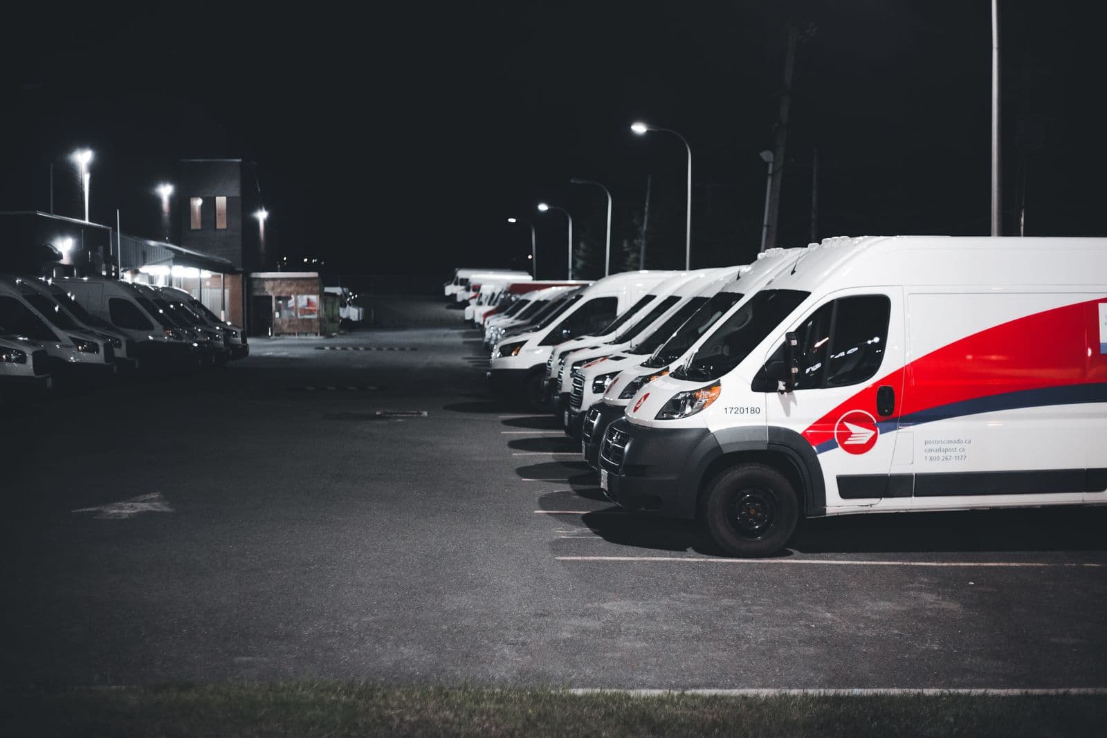 A row of white vans parked at night